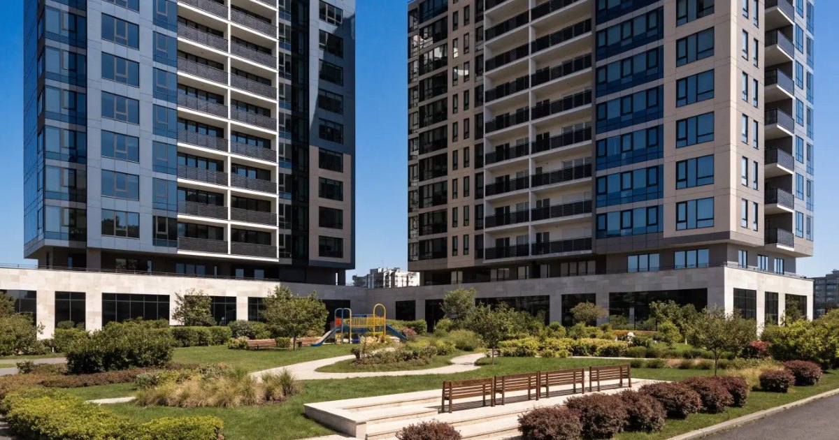 Two modern Etobicoke condominium towers above a landscaped courtyard with benches and a small playground