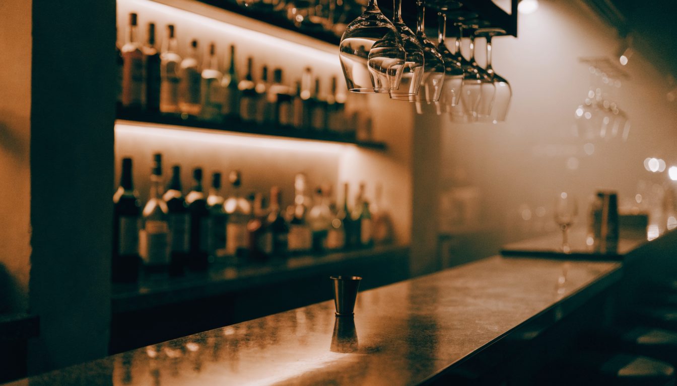 Restaurant bar counter with bottles on backlit shelves (illustrative)