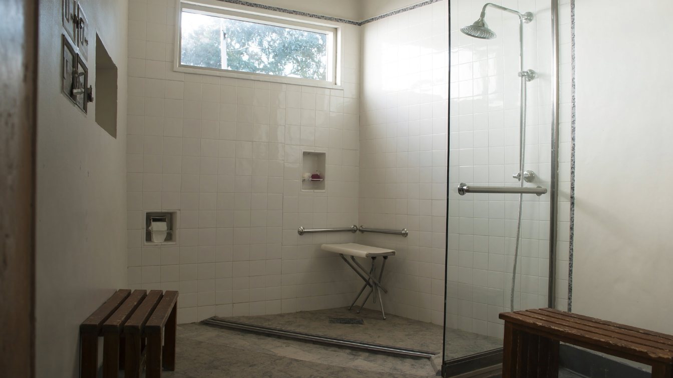 Accessible bathroom with a curbless walk-in shower, grab bars and a fold-down seat in a family home (illustrative)