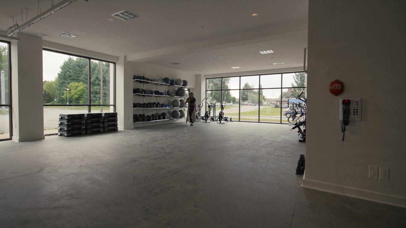 Empty fitness studio with weight racks, rowing machines and rubber flooring in a GTA plaza unit (illustrative)