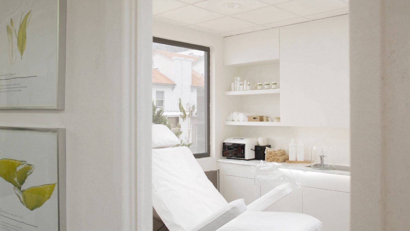 Bright aesthetic clinic treatment room with a reclining treatment chair and skincare shelves in a GTA plaza (illustrative)