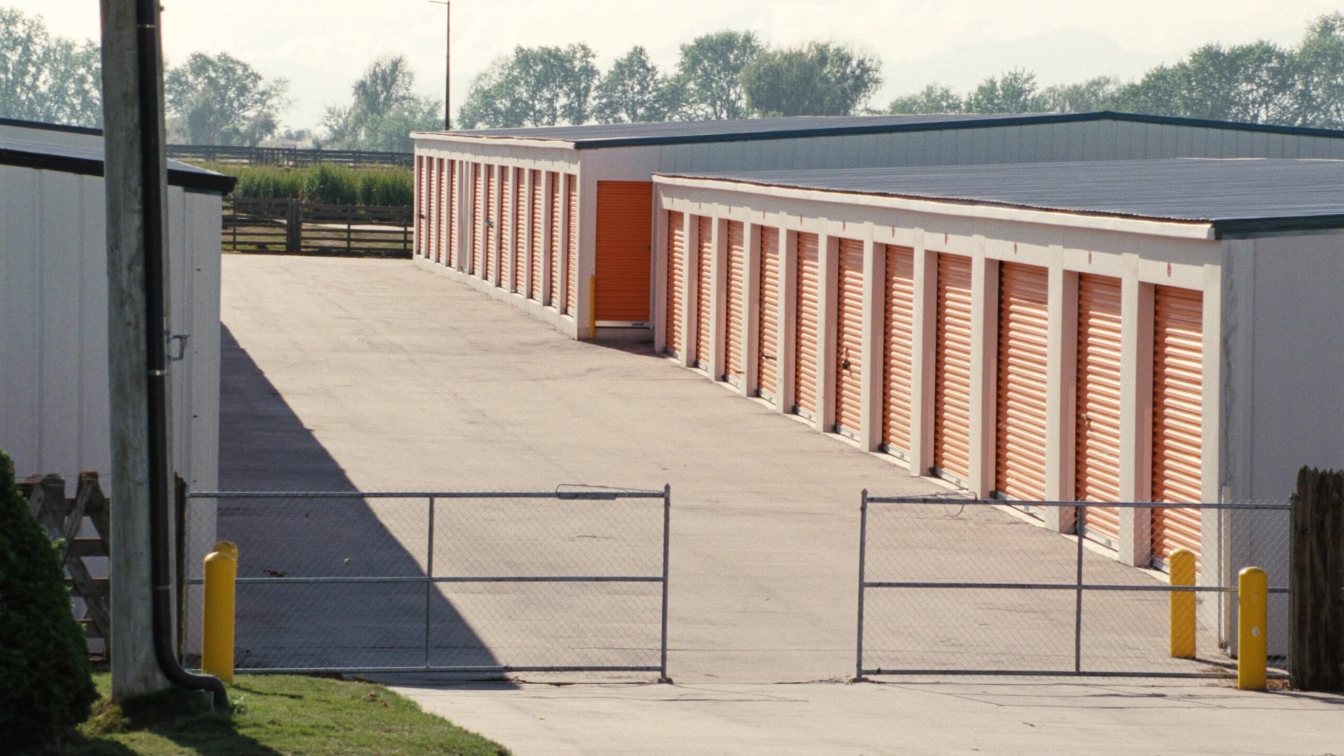 Single-storey self-storage buildings with rows of roll-up unit doors and a gated drive aisle in a GTA employment area (illustrative)