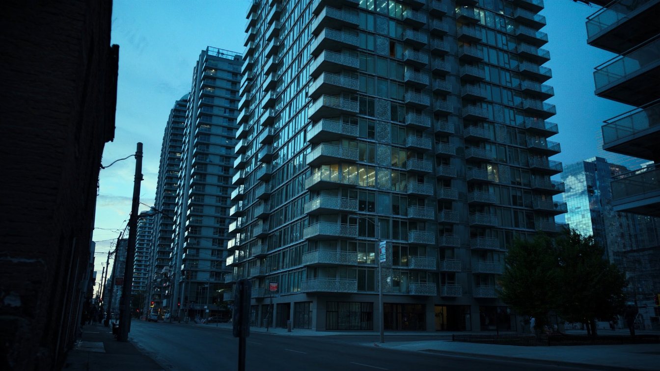 A tall glass condominium tower with patterned balcony glass on a downtown Toronto side street (illustrative)