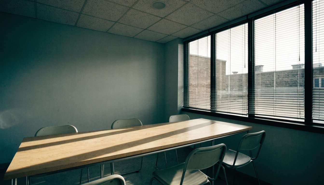 An empty meeting room with two chairs at a bare table, illustrating the difference between a client and a self-represented party.