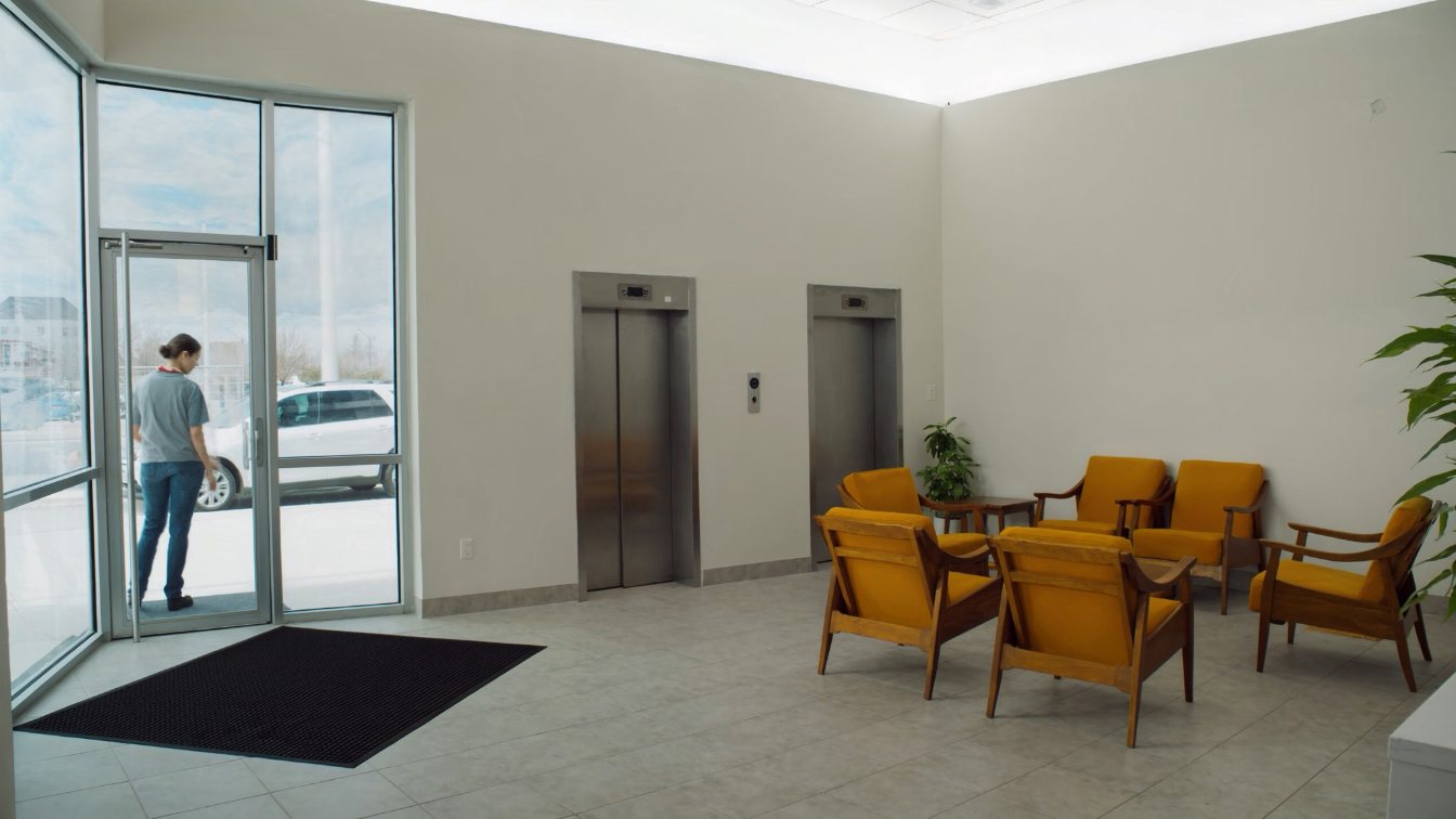 Bright condominium lobby with a wide entrance, seating area and two elevator doors (illustrative)
