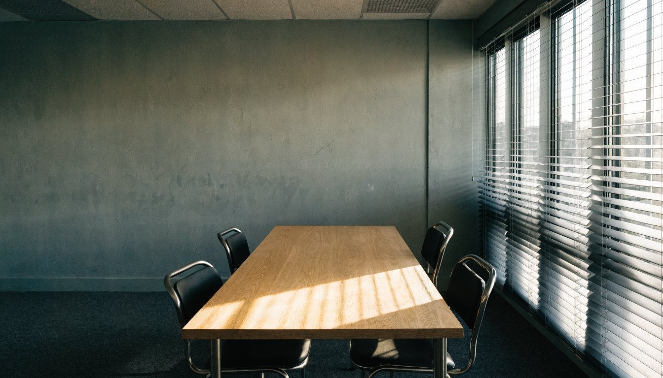 An empty institutional meeting room with a long plain table, illustrating deposits held in a brokerage trust account.