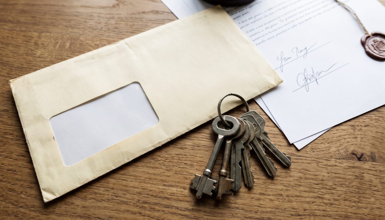 A bank draft envelope, house keys and a signed agreement of purchase and sale on a desk (illustrative)