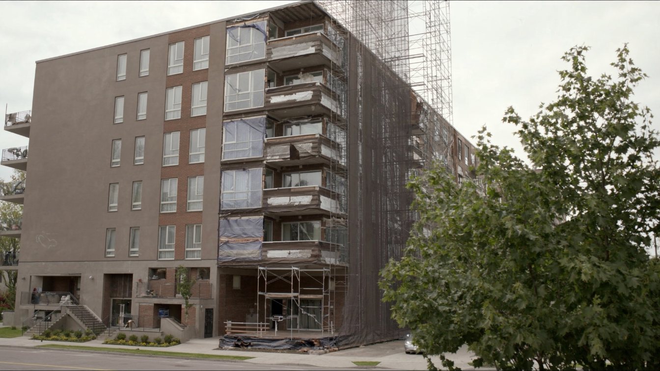 Condominium building exterior with scaffolding on one facade during repairs (illustrative)