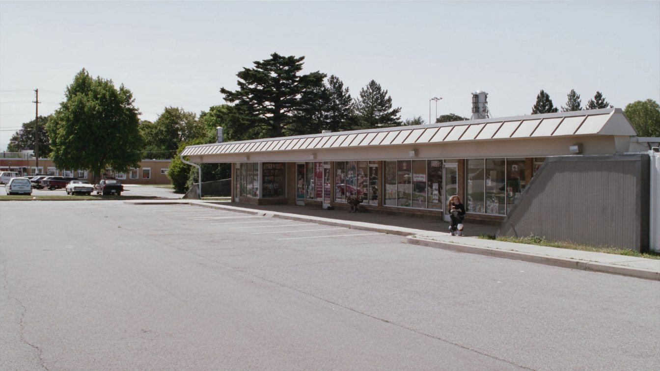 Suburban strip plaza with a row of storefronts and a parking lot in the GTA on an overcast day (illustrative)