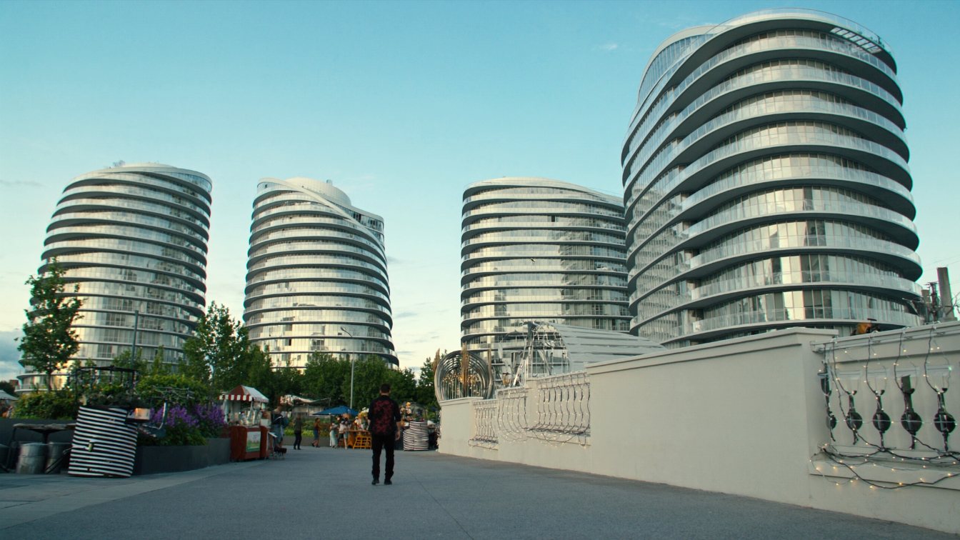 Four glass condominium towers of different heights around an open-air retail promenade in a new downtown district (illustrative)
