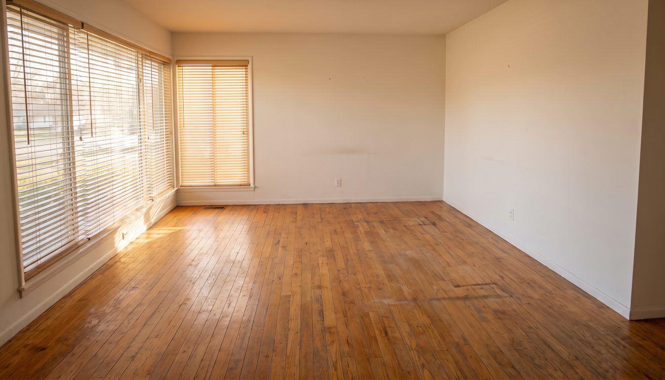 An empty living room with bare floors and open blinds the day before closing (illustrative)