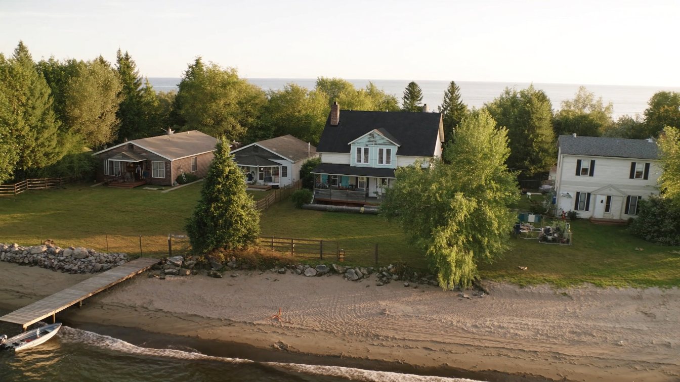 Sandy Lake Simcoe shoreline with cottages and mature trees on a calm summer evening in Georgina (illustrative)