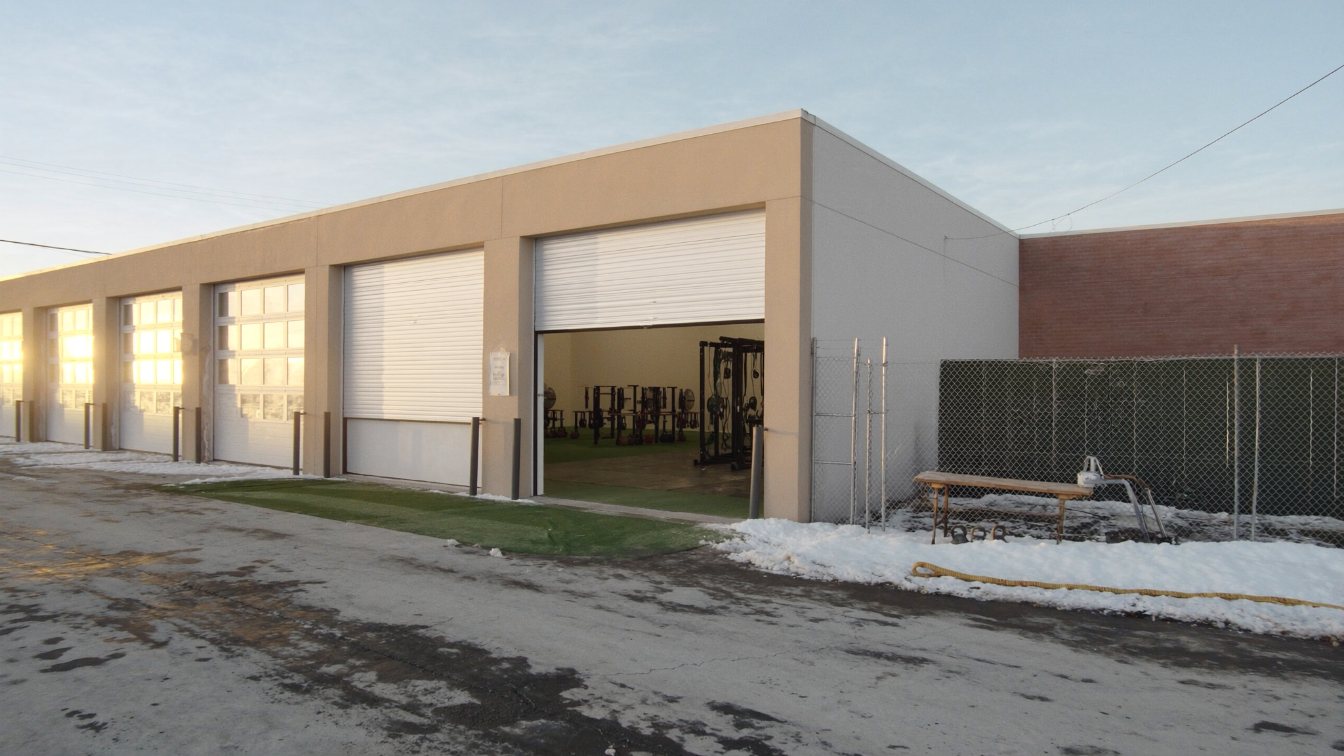 Industrial condo unit with a roll-up door converted into a strength-training gym, in a GTA business park (illustrative)