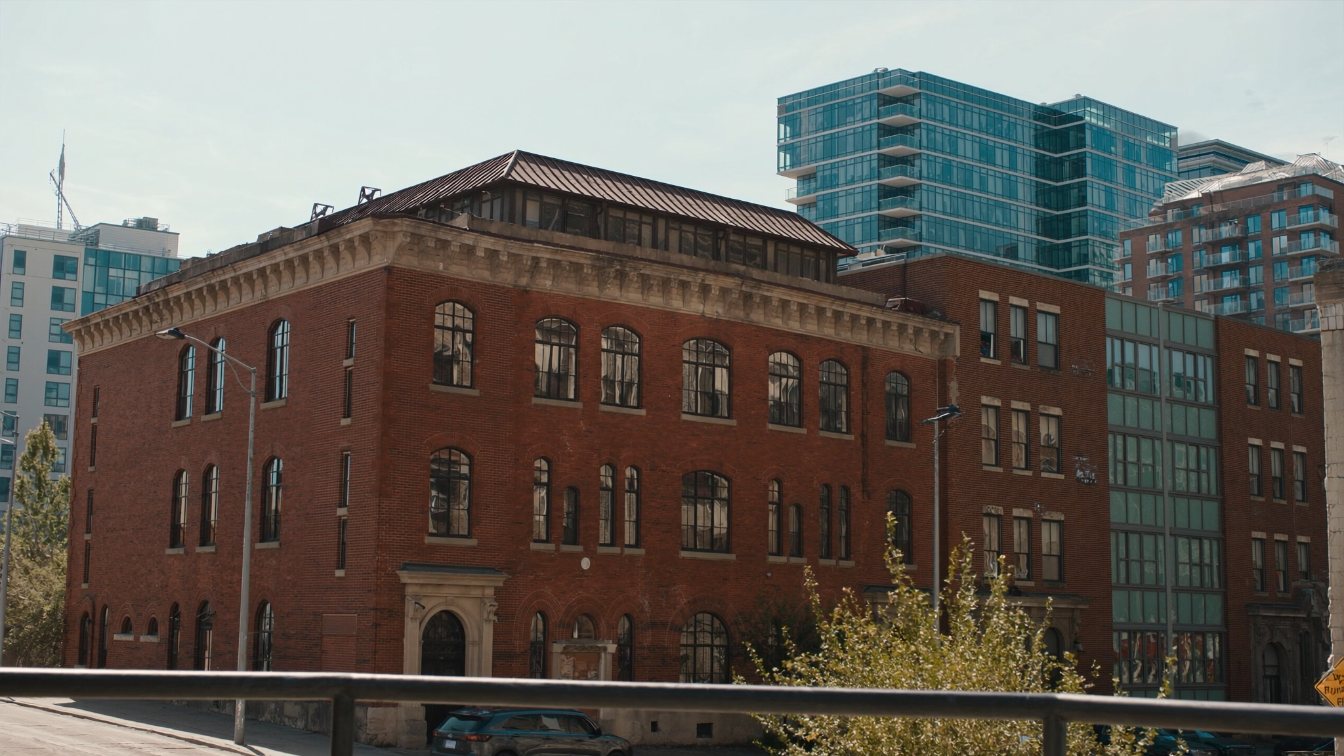 Converted brick loft building beside newer glass condominium towers in Toronto's west downtown (illustrative)