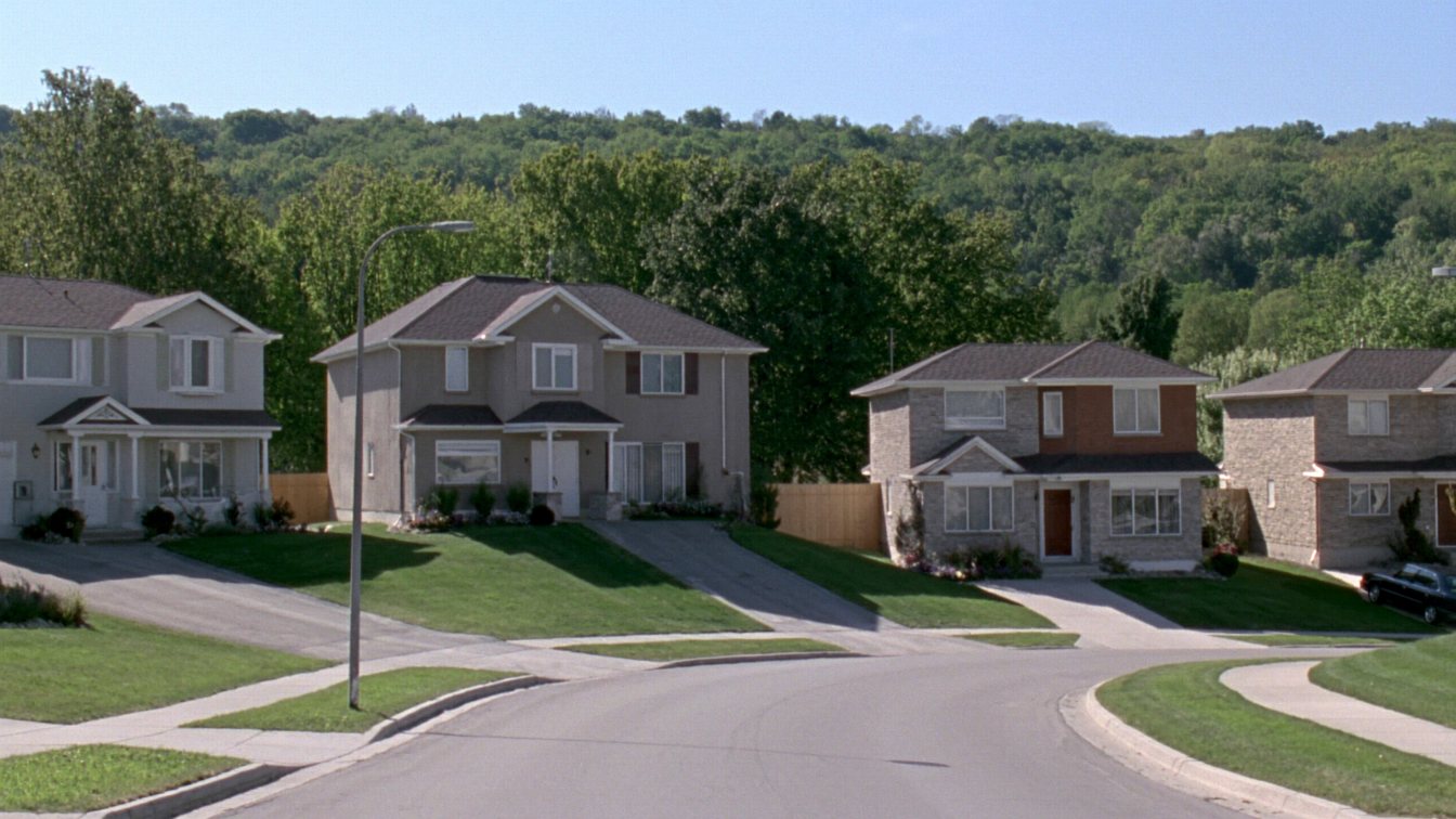 Detached family homes on a quiet Burlington street with the Niagara Escarpment in the distance (illustrative)