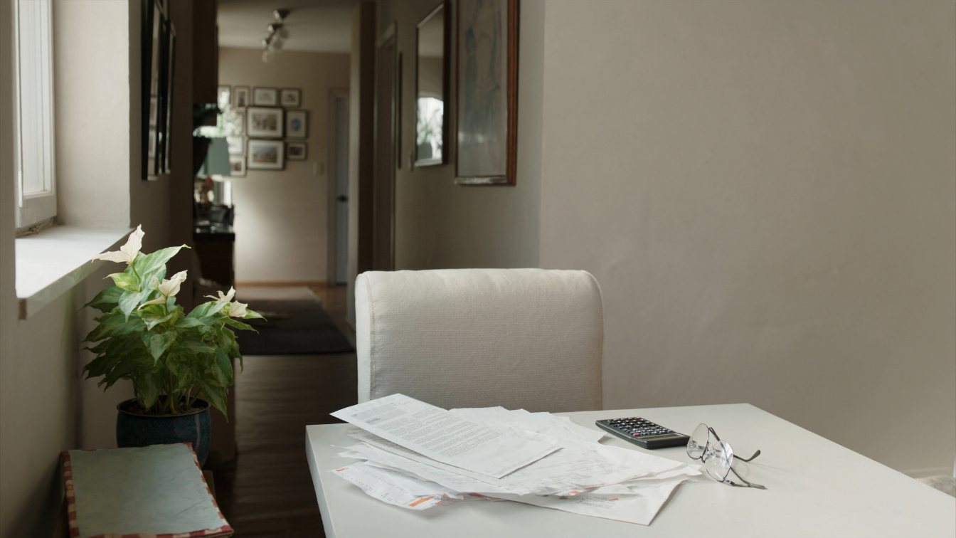 Older couple's hands going over household bills at a kitchen table in a Toronto home (illustrative)