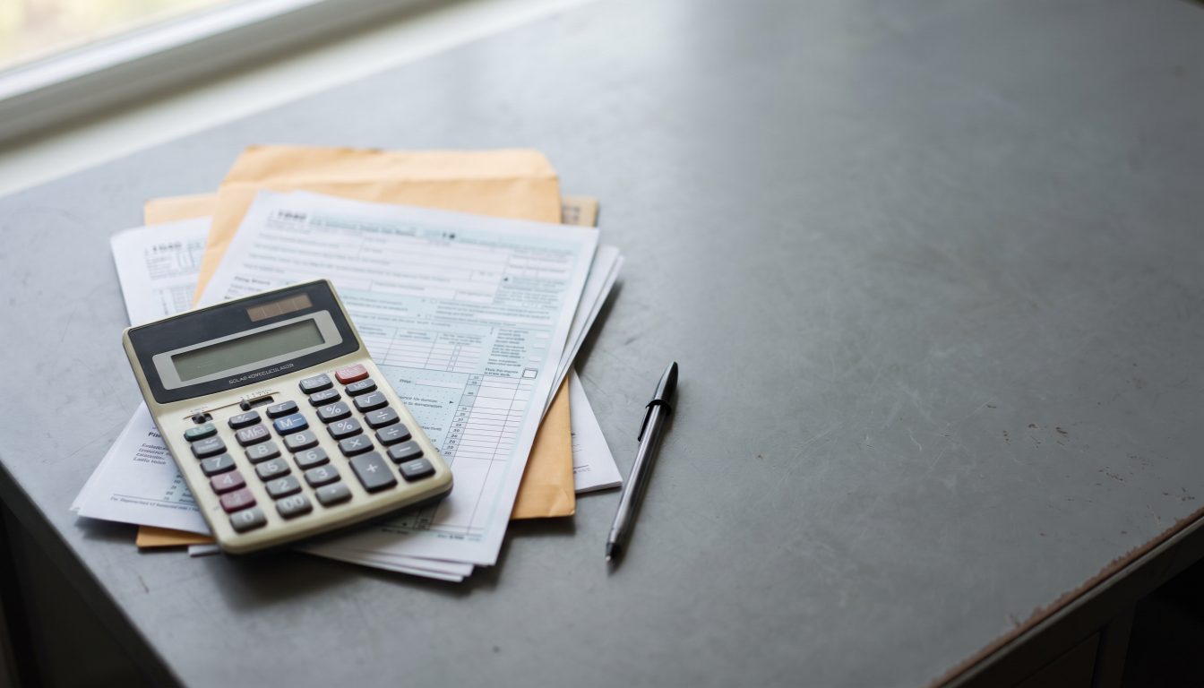 A commercial property file open beside a schedule to an agreement of purchase and sale, a calculator and a pen