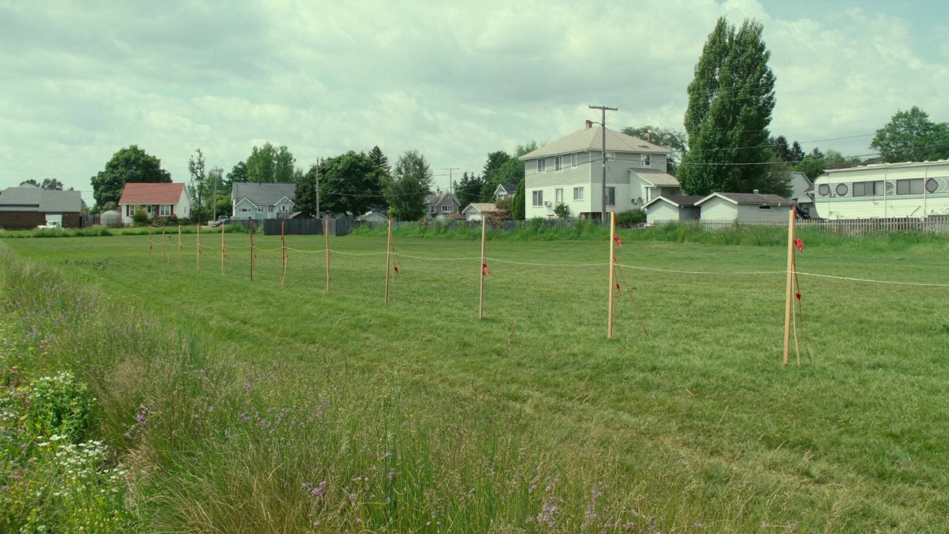 Surveyed vacant lots divided by stakes and string on the edge of an Ontario town (illustrative)