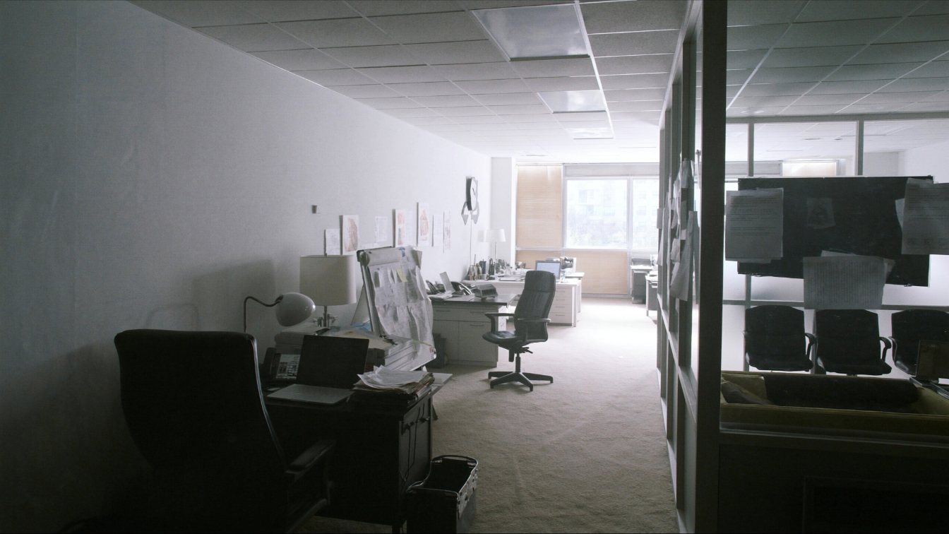 Open-plan professional office with desks and a small meeting room behind glass (illustrative)