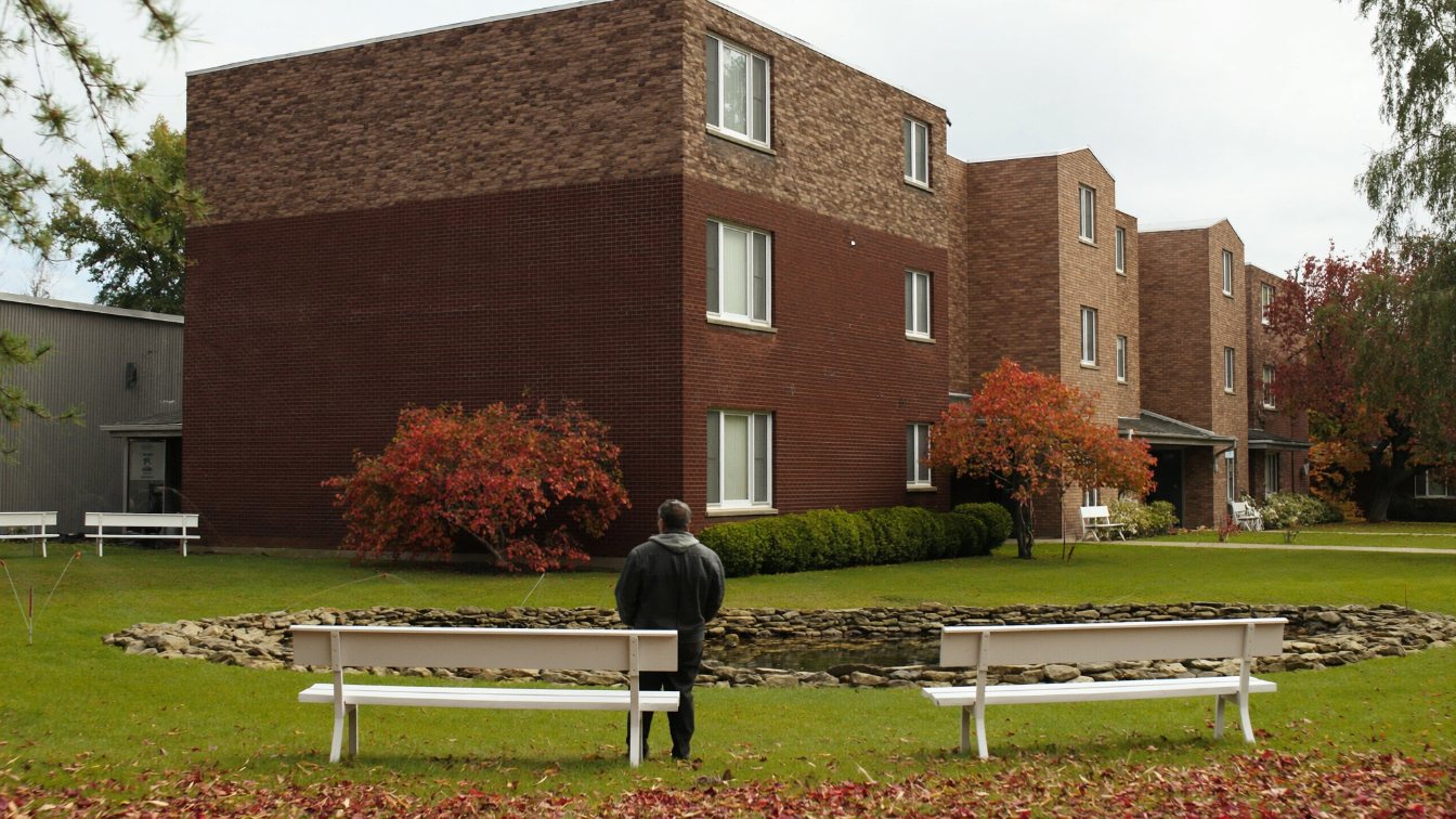 Low-rise seniors apartment building with a landscaped garden and benches in autumn (illustrative)