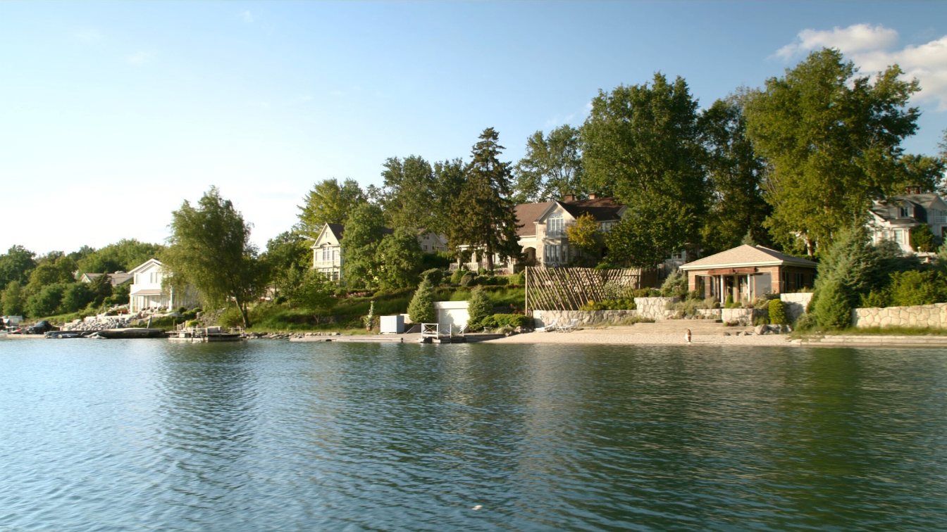 A narrow tree lined lane with large houses on wooded lots near the Lake Ontario shore (illustrative)