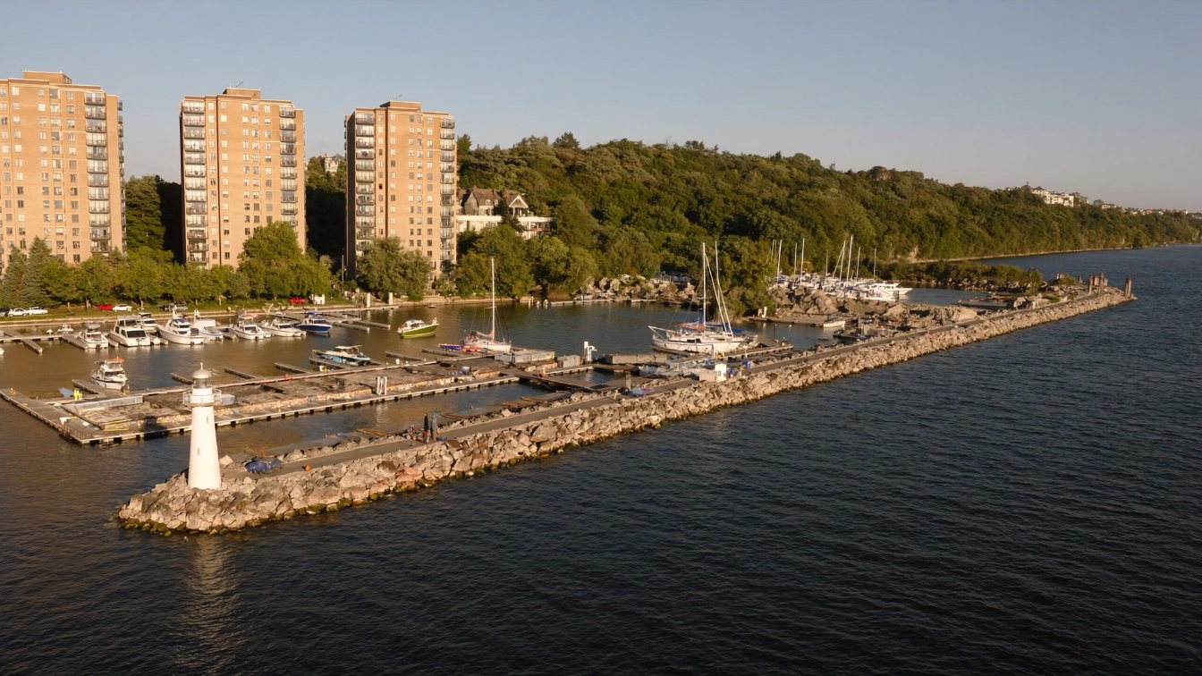 Port Credit lighthouse and marina with condominium buildings behind and the Lorne Park shoreline in the distance (illustrative)