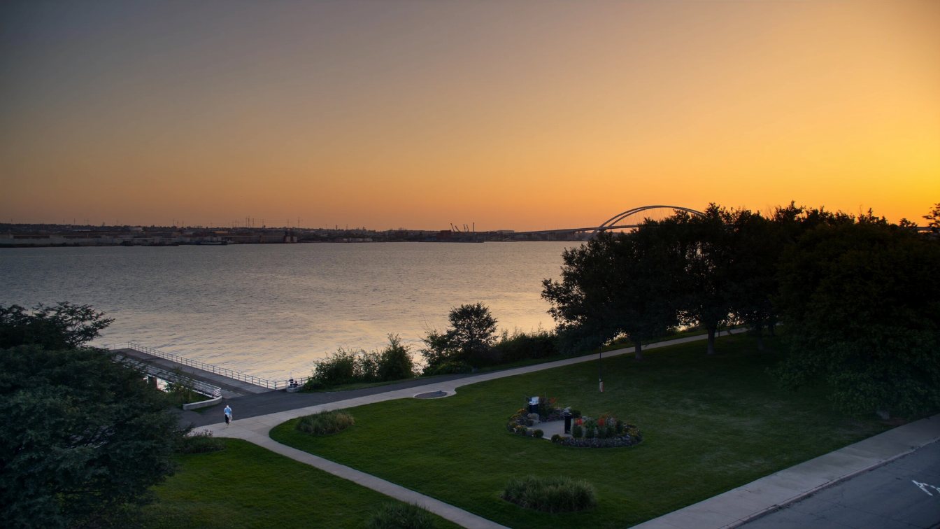 Burlington waterfront promenade with the Skyway bridge and Hamilton shoreline in the distance at sunset (illustrative)