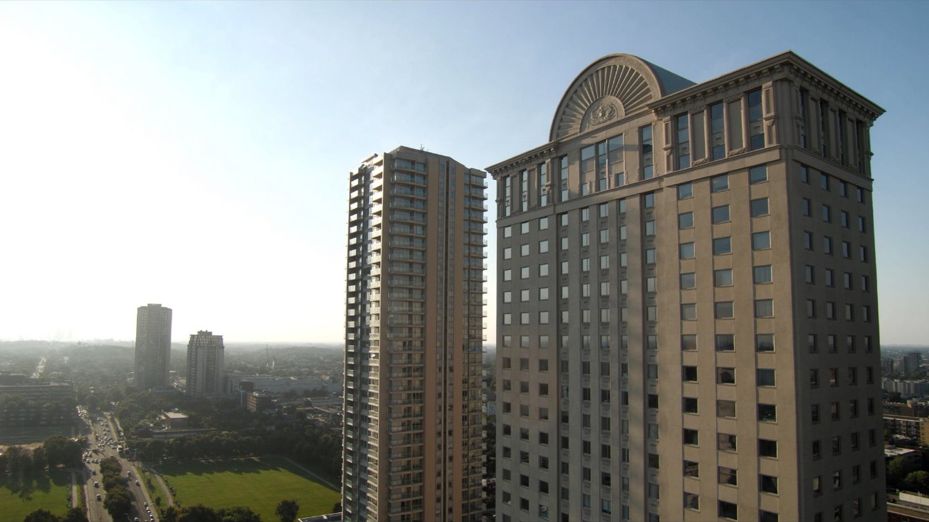 Classically styled high-rise condominium tower with arched details beside a park in a suburban downtown (illustrative)