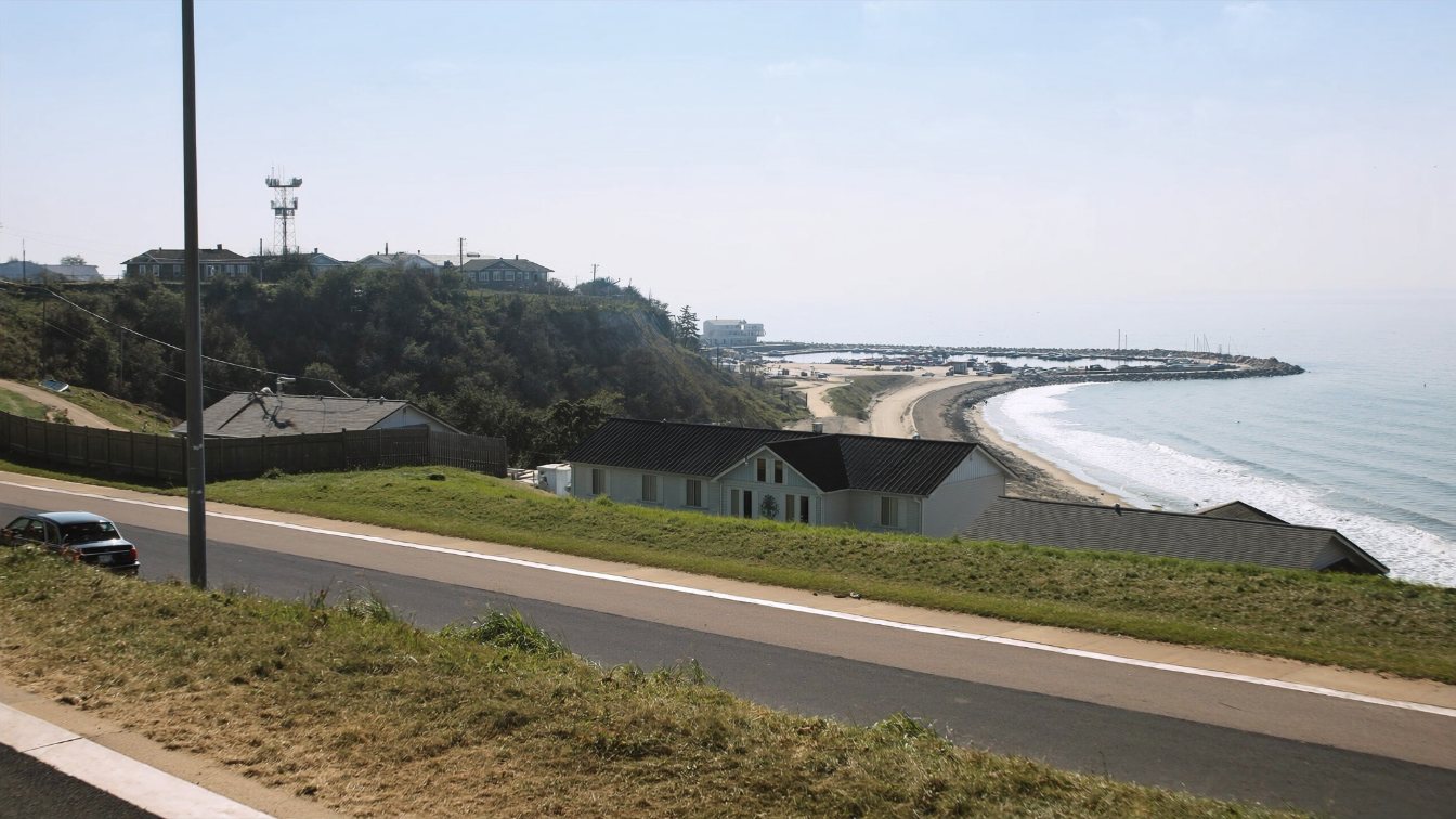 Sand beach and bluff shoreline with a small harbour and marina in the distance on Lake Ontario in Durham Region (illustrative)