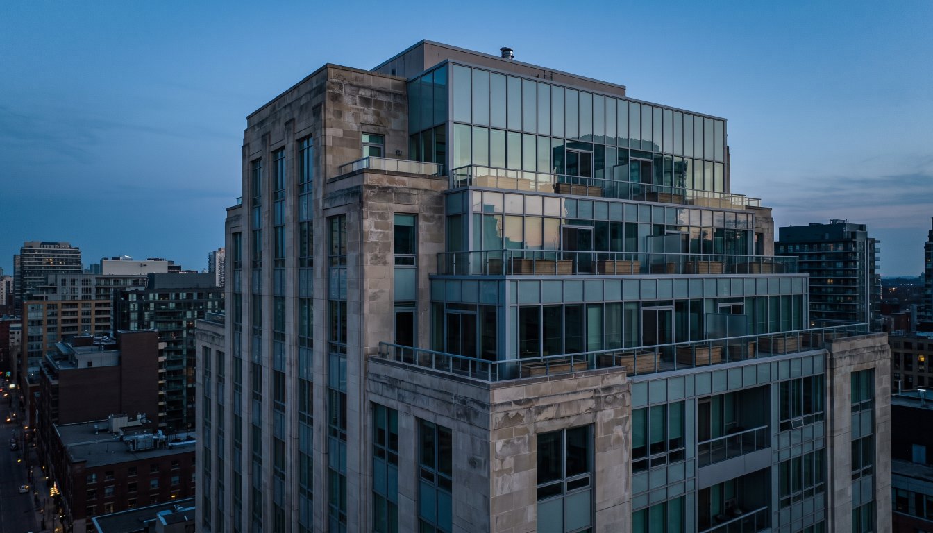 The upper floors of a limestone and glass luxury condominium tower in Toronto with deep terraces