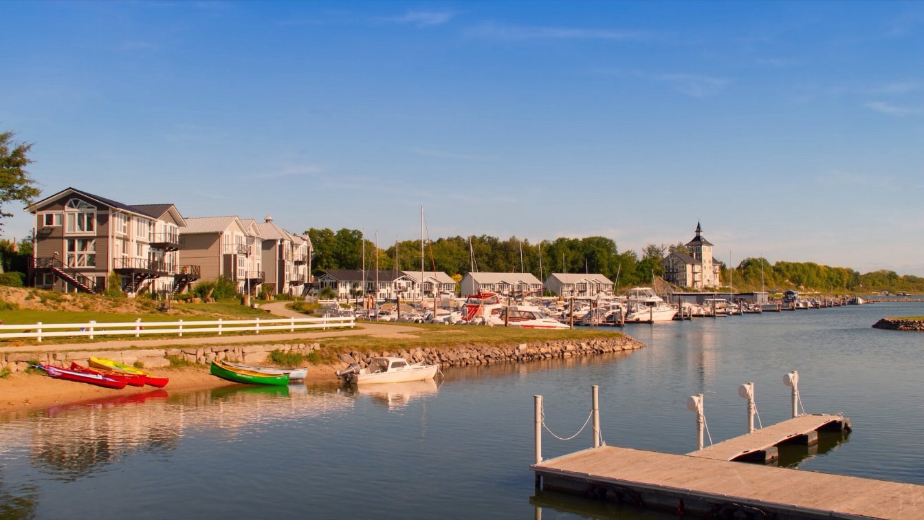 Lakefront trail along Lake Ontario with a harbour and low-rise homes in the distance in Durham Region (illustrative)