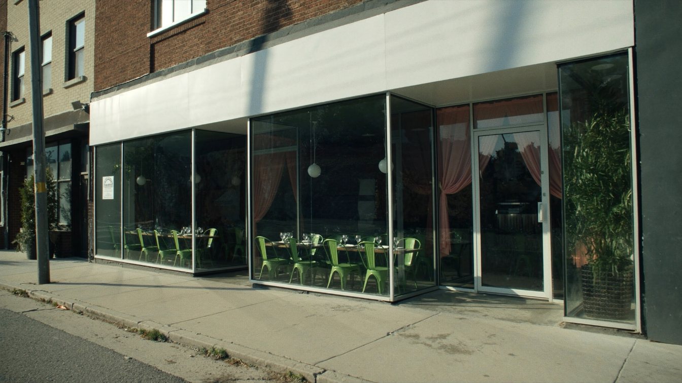 Closed restaurant storefront on a Toronto commercial street with the dining room visible through the window (illustrative)