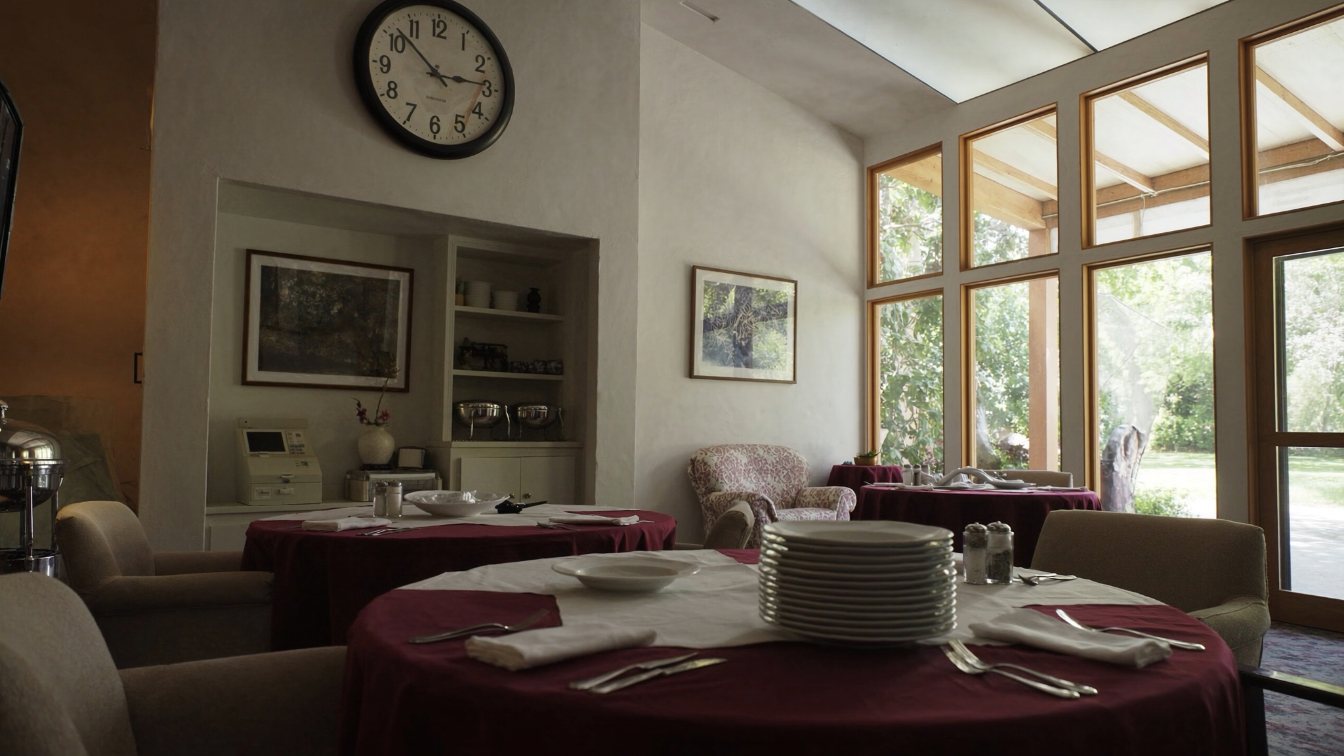 Dining room with set tables and large windows in a seniors residence (illustrative)