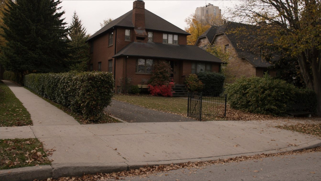 Quiet tree-lined midtown Toronto residential street with older brick houses and a mid-rise building behind in autumn (illustrative)