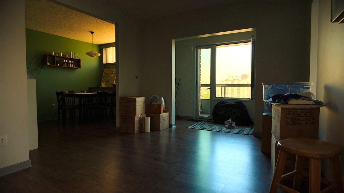 Bright rental apartment living room with boxes from a move and a view over Toronto (illustrative)