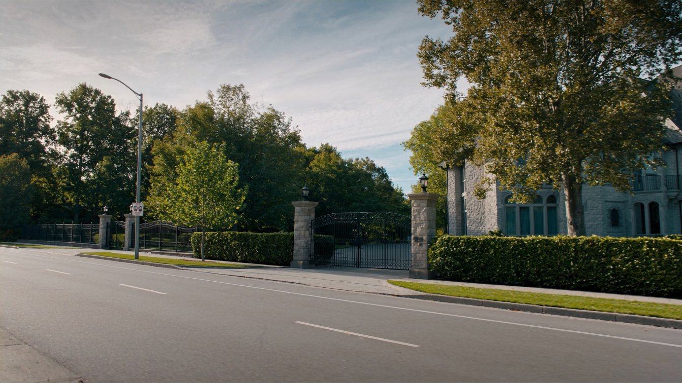 A large limestone detached house in Toronto set behind a low stone wall and mature garden (illustrative)