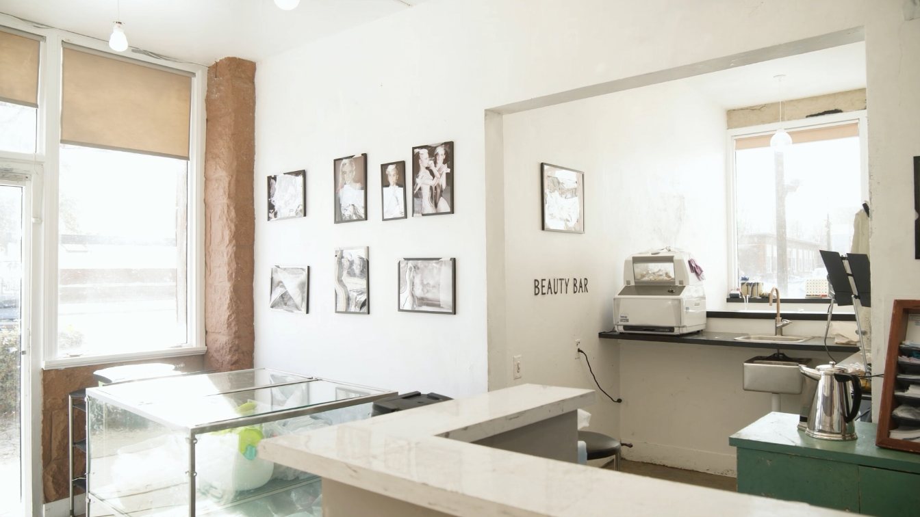 Small street-front studio space with a separate back room for equipment cleaning and sterilization, empty and bright (illustrative)