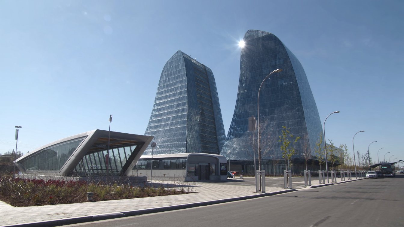Twin slender glass condominium towers beside a subway station and bus terminal in a new suburban downtown (illustrative)