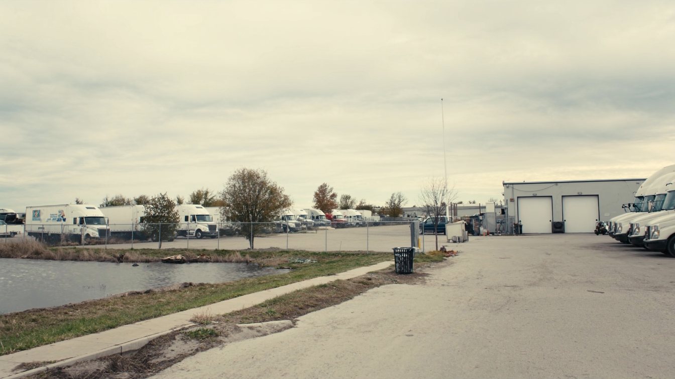 Paved truck parking yard with trailers, perimeter fencing, a stormwater pond and a small maintenance garage in Peel Region (illustrative)
