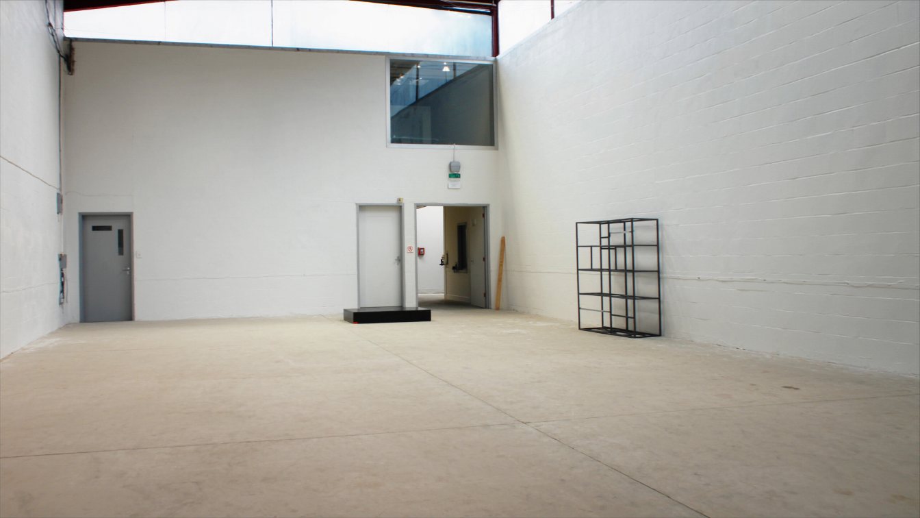 Interior of a light industrial warehouse unit with racking, a dock door and an office mezzanine (illustrative)