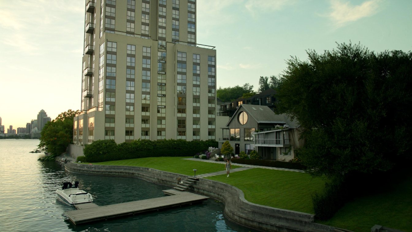 Split view of a lakefront condominium tower and a detached lakefront house on the Lake Ontario shoreline (illustrative)