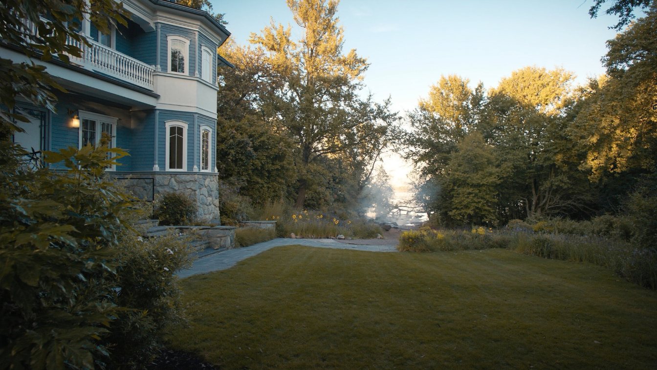 Substantial two-storey house on a deep lot with mature trees and Lake Ontario visible at the end of the garden (illustrative)