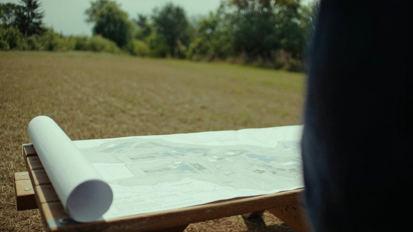 A zoning map and site plan spread on a table beside a vacant Ontario lot (illustrative)