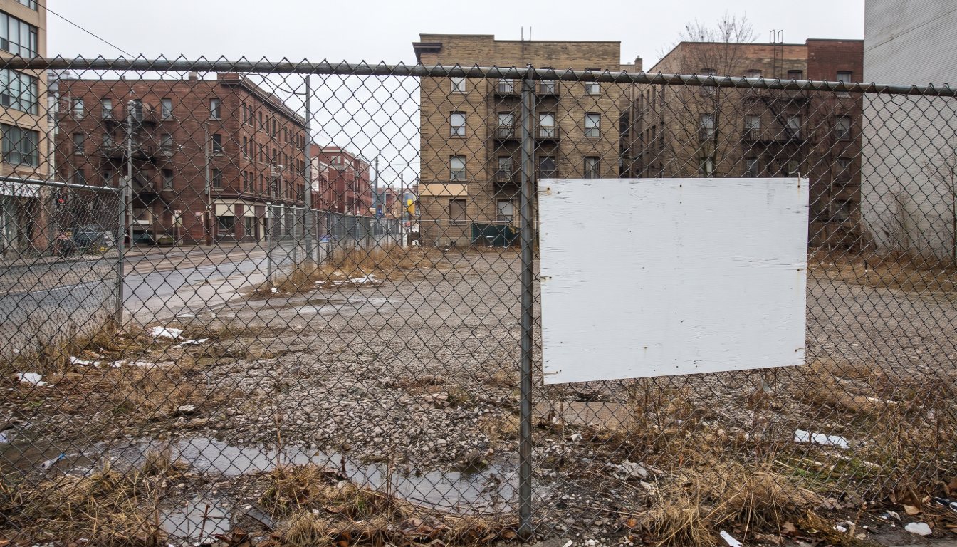 A fenced vacant development lot in Toronto with a proposal sign board