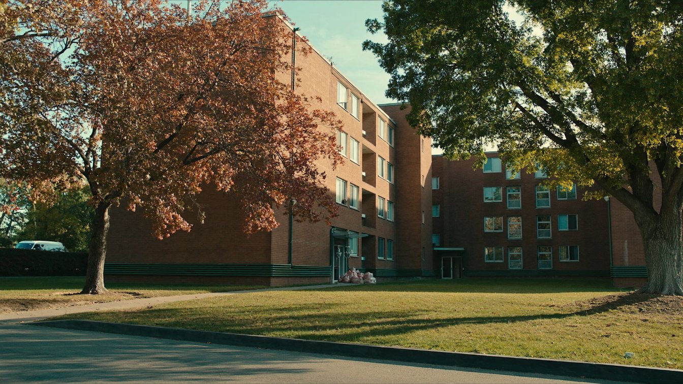 1970s brick apartment tower behind mature trees in a quiet Etobicoke neighbourhood (illustrative)