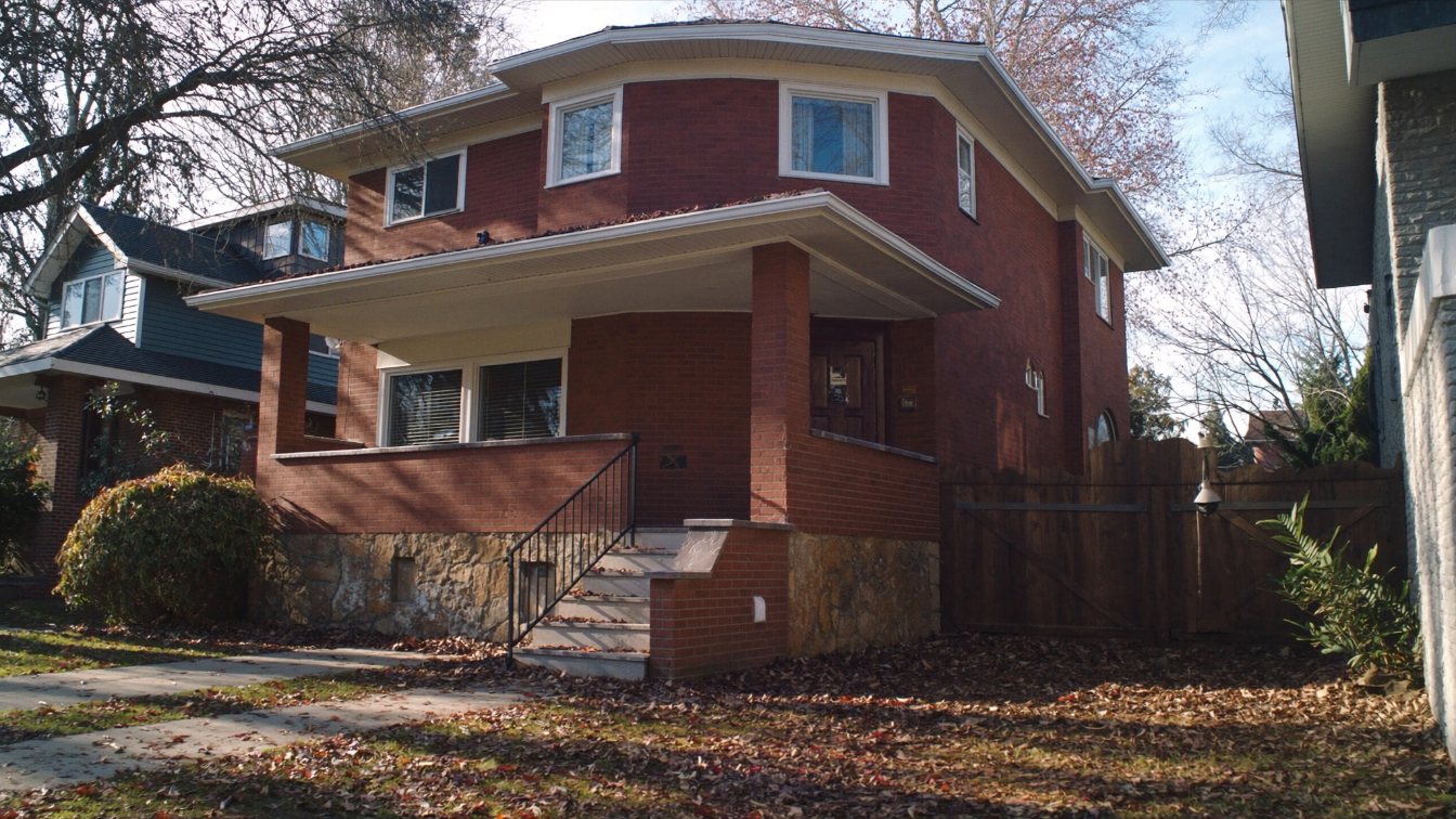 A semi-detached brick home with a front porch on a tree-lined Toronto street in autumn (illustrative)
