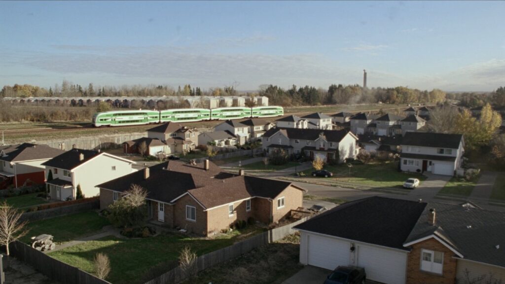 A street of two-storey detached homes and townhouses in a Durham Region suburb with a GO train line in the distance (illustrative)
