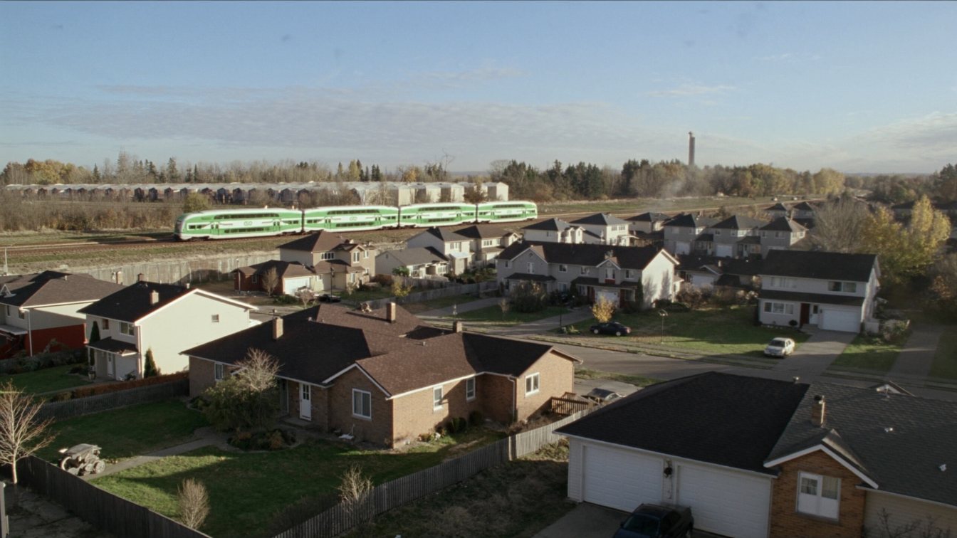 A street of two-storey detached homes and townhouses in a Durham Region suburb with a GO train line in the distance (illustrative)