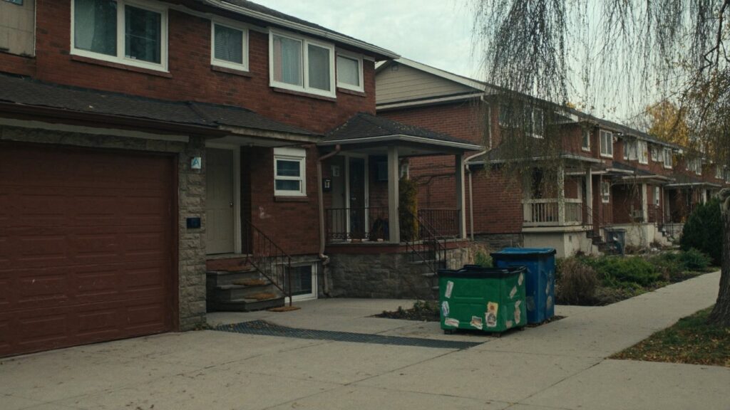 A row of brick freehold townhouses with small front gardens on a quiet GTA residential street in autumn (illustrative)