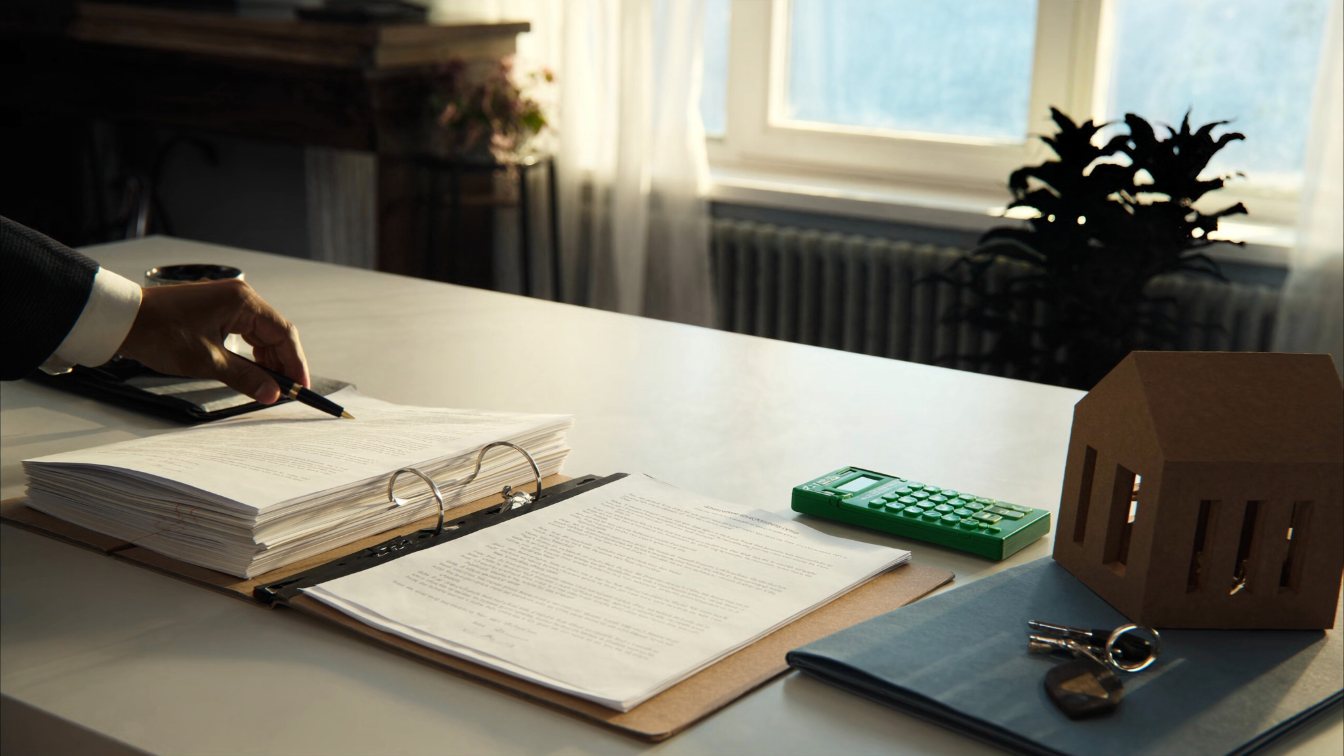 Buyers signing closing documents with keys and a calculator on the desk (illustrative)